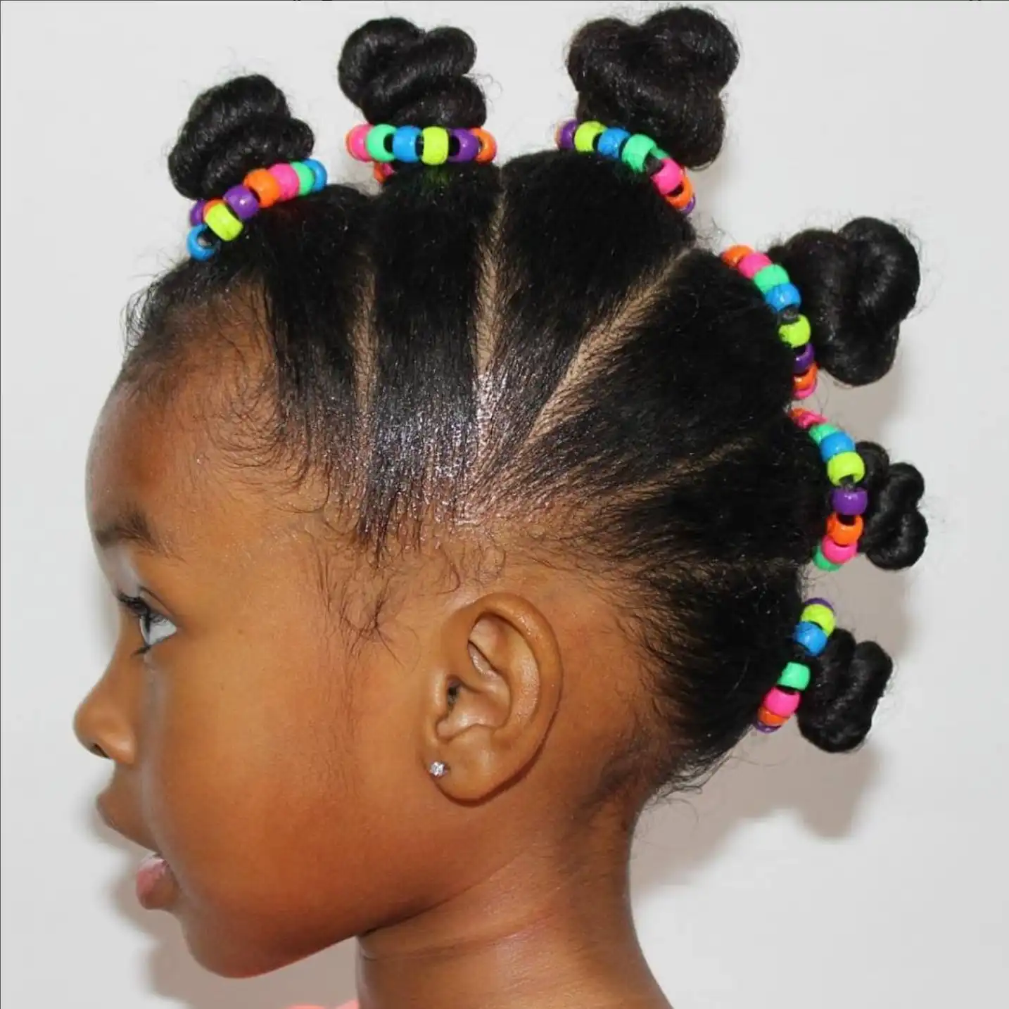 Idées de coiffure afro pour fillette: Bantu knots en mohawk avec perles colorées